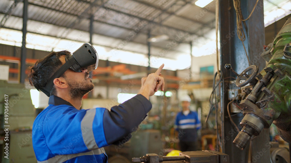 Engineer wearing virtual reality headset standing in the manufacturing factory. Moving hand and looking around the data. Working with Holographic Animations. High technology and industrial concept Engineer wearing virtual reality headset standing in the manufacturing factory. Moving hand and looking around the data. Working with Holographic Animations. High technology and industrial concept