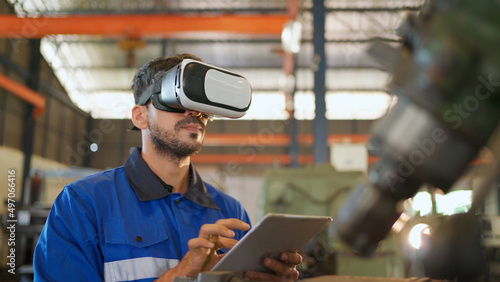 Engineer wearing virtual reality headset standing in the manufacturing factory. Moving hand and looking around the data. Working with Holographic Animations. High technology and industrial concept