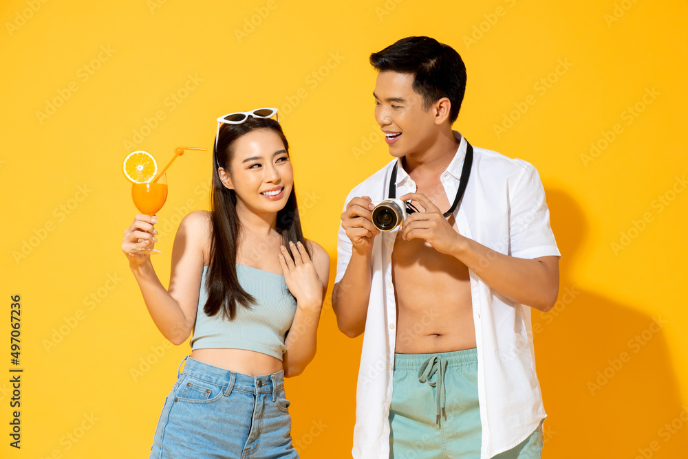 Summer portrait of happy young Asian couple in studio isolated yellow color background Summer portrait of happy young Asian couple in studio isolated yellow color background
