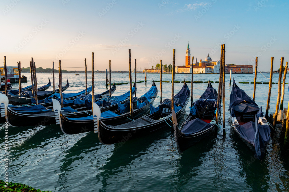 Venice, Italy - July 28 2021: Canals with boats and gondolas in Venice, Italy during sunrise