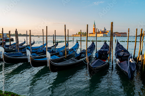 Venice, Italy - July 28 2021: Canals with boats and gondolas in Venice, Italy during sunrise © valdisskudre