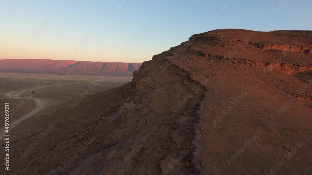 Drone flying over rocky formation in desert with red mountain in background at sunset, Morocco. Aerial fpv
Drone flying over rocky formation in desert with red mountain in background at sunset, Morocco. Aerial fpv