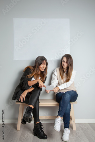 Obraz na plátne Mujeres mirando un folleto. Chicas eligiendo en un local