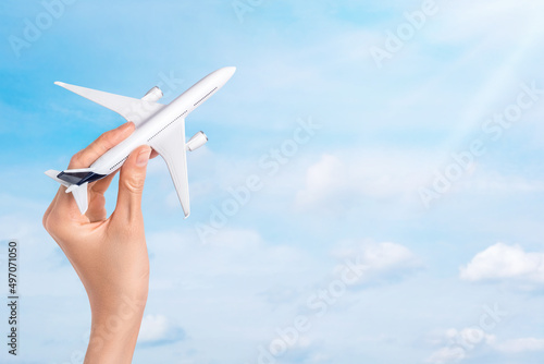 Hand holding airplane over blue sky background. Flight, travel concept