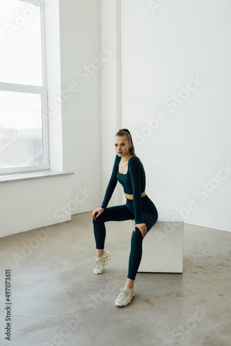 Fit young woman sitting on a box after exercising. Woman wearing sports clothing looking at camera