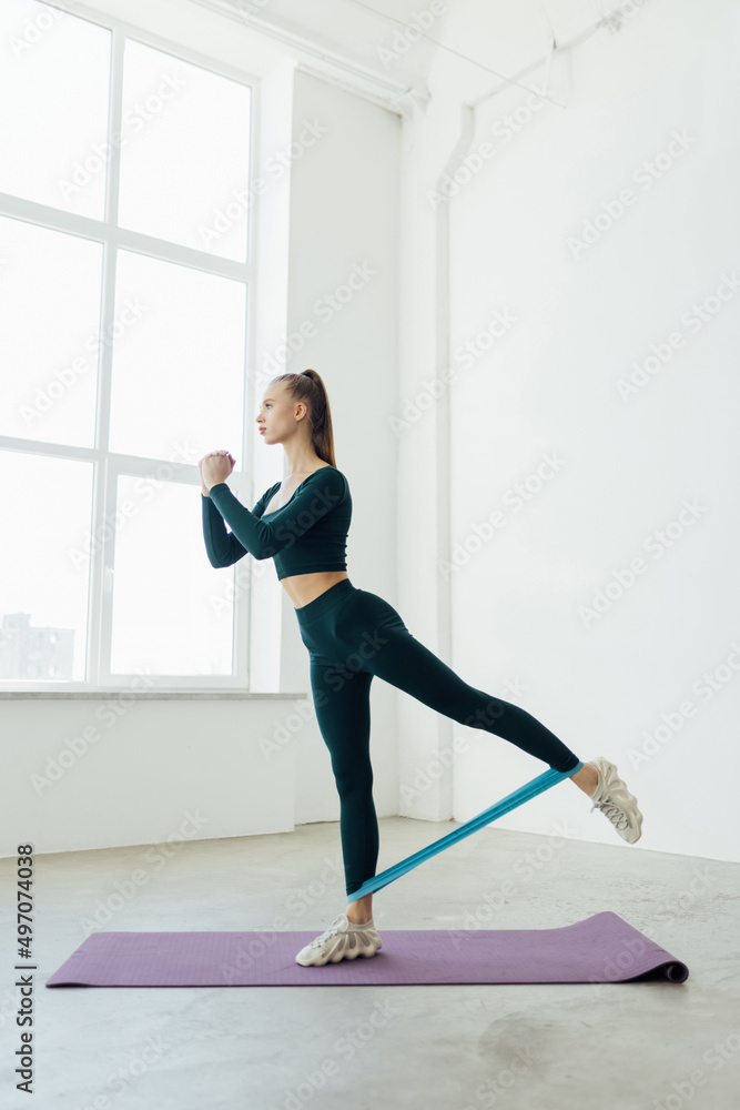 Young Woman during her fitness workout at home with rubber resistance band