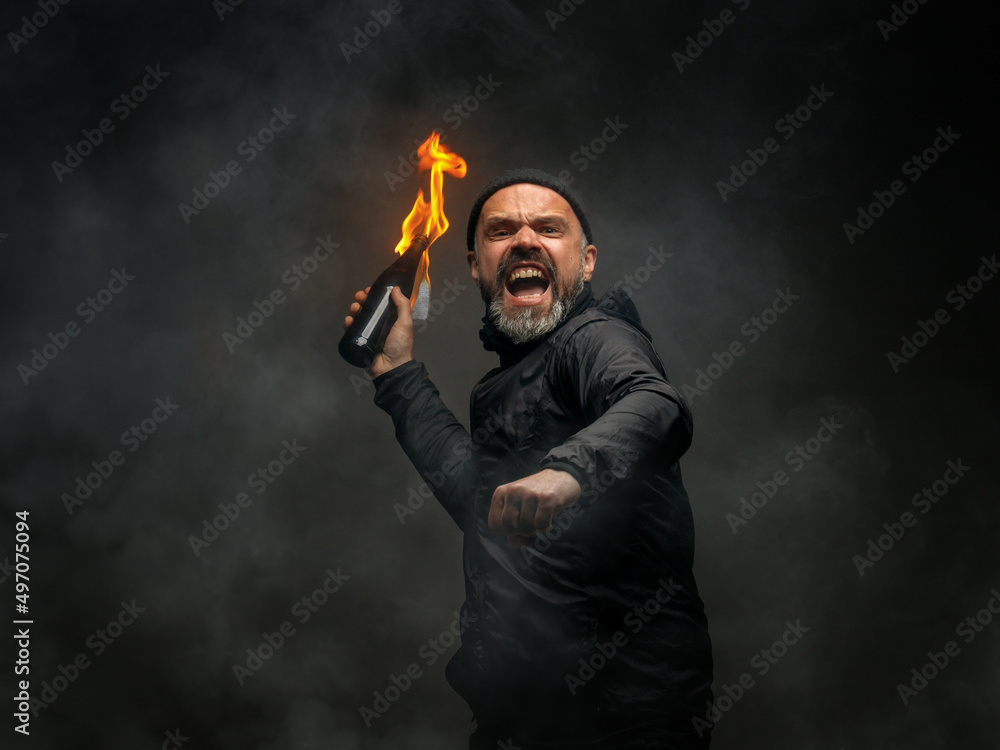 emotional portrait of a man with a molotov cocktail in his hands. a man throws a Molotov cocktail. the concept of protest and resistance emotional portrait of a man with a molotov cocktail in his hands. a man throws a Molotov cocktail. the concept of protest and resistance