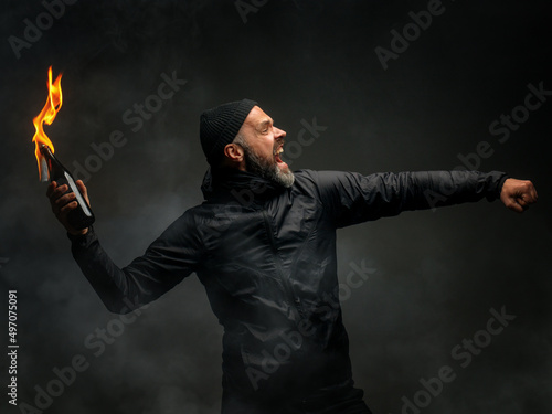 emotional portrait of a man with a molotov cocktail in his hands. a man throws a Molotov cocktail. the concept of protest and resistance photo