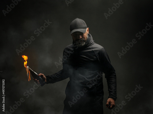 emotional portrait of a man with a molotov cocktail in his hands. a man throws a Molotov cocktail. the concept of protest and resistance photo