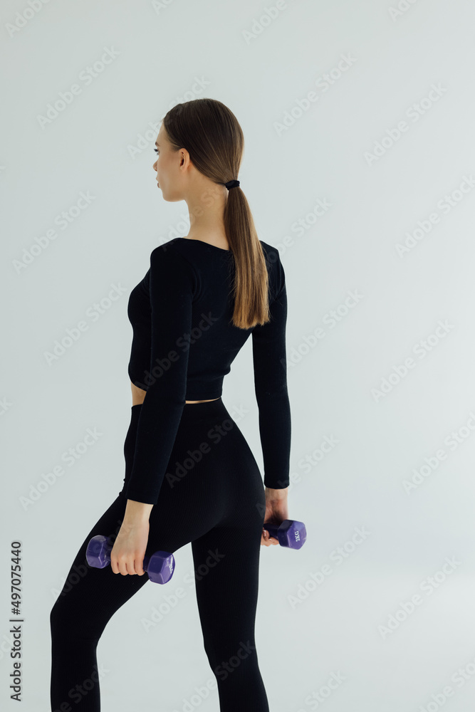 Sporty woman doing exercises, making direct hit with dumbbells. Muscular female wearing sportswear on white background. Strength and motivation Sporty woman doing exercises, making direct hit with dumbbells. Muscular female wearing sportswear on white background. Strength and motivation