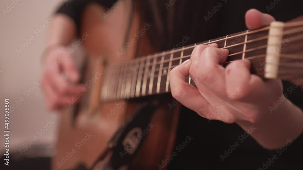 Acoustic guitar fretboard and hand playing chords, close up view with no face Acoustic guitar fretboard and hand playing chords, close up view with no face