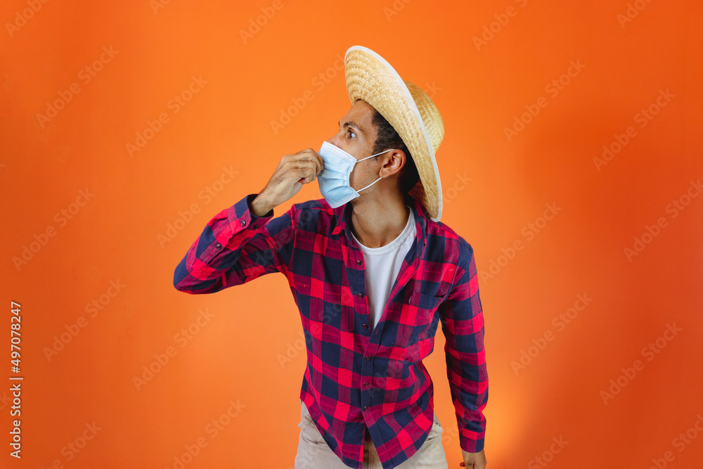 Black Man With Junina Party Outfit with pandemic mask Isolated on Orange Background. Black Man With Junina Party Outfit with pandemic mask Isolated on Orange Background.
