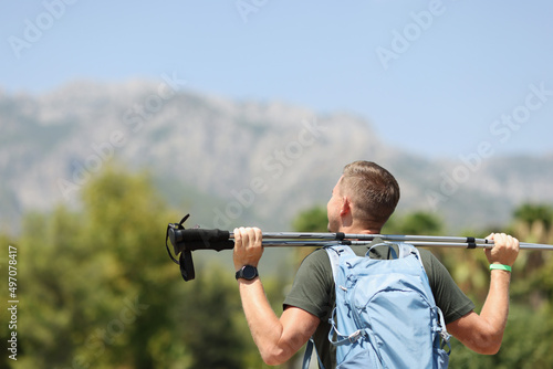 Man holds trekking stick on mountain closeup
