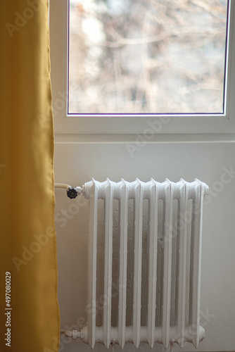 Wallpaper Mural white battery on the wall. Iron radiator against the background of a white wall and yellow curtains Torontodigital.ca