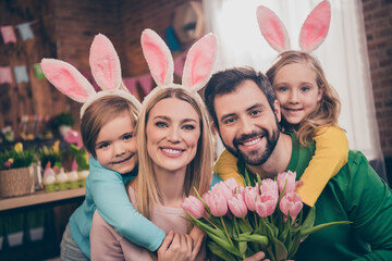Photo of cute lovely family with bunny ears celebrate easter holiday father hold present for mother bunch of flowers