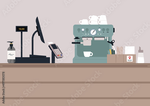 A coffeeshop counter with a register and a pos terminal, a coffee machine with cups on top of it, a hand sanitizer bottle, a sugar dispenser and a stack of napkins