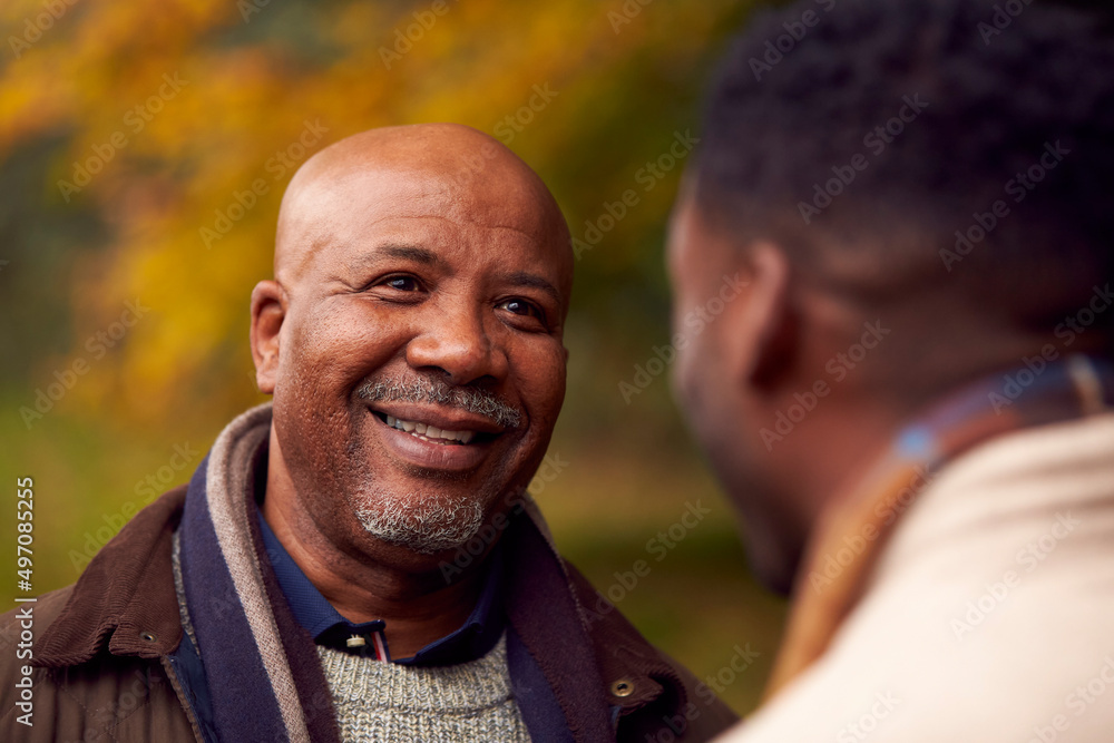 Senior Father Talking With Adult Son On Walk Through Autumn Countryside Senior Father Talking With Adult Son On Walk Through Autumn Countryside