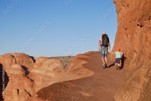 Father and son hiking on Delicate Arch trail at sunset. Family on summer vacation trip. Arches National Park, Moab, Utah, USA.