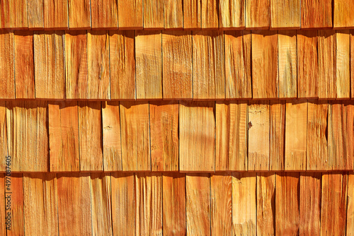 the texture of the wooden shingles covering the wall of the house