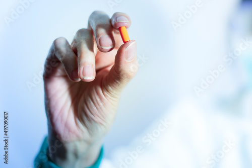 Pill close-up. Doctor's hand holding antiviral pill. Medicine. Orange pill. Treatment against disease. Health and disease concept. Covid 19 treatment