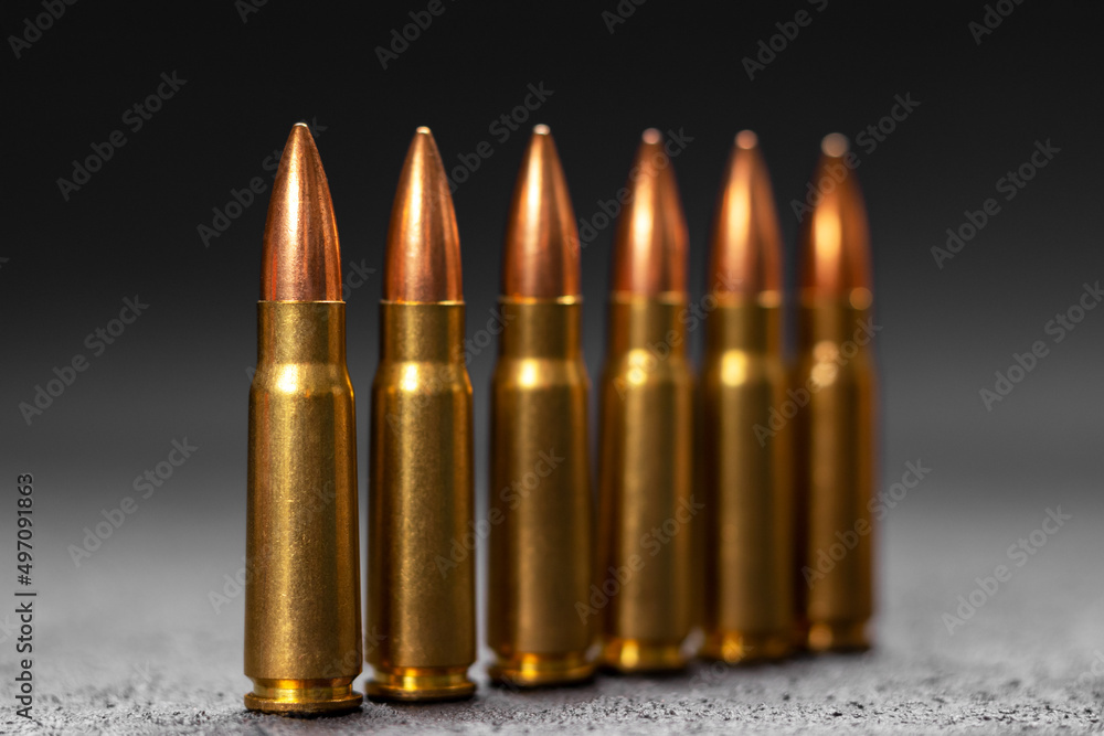 Bullets on gray background. Cartridges 7.62 caliber for Kalashnikov assault rifle. Selective focus Bullets on gray background. Cartridges 7.62 caliber for Kalashnikov assault rifle. Selective focus