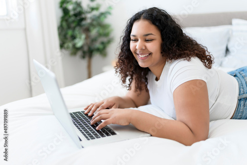 girl using laptop in bed during morning time at home