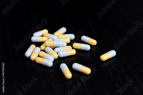 Pills on a black wooden table, medication in capsules. Pharmacy, antibiotics or vitamins