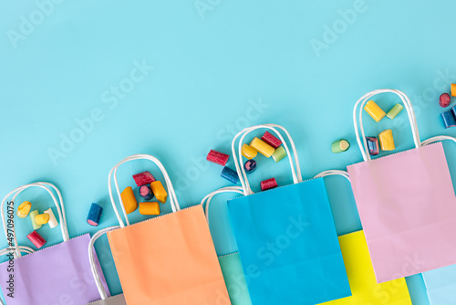 Flat lay, paper bags and chewing gummies on a blue background.