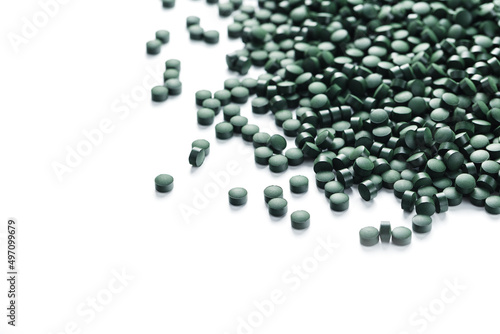 Vegetarian vitamins from Spirulina are scattered on a white background