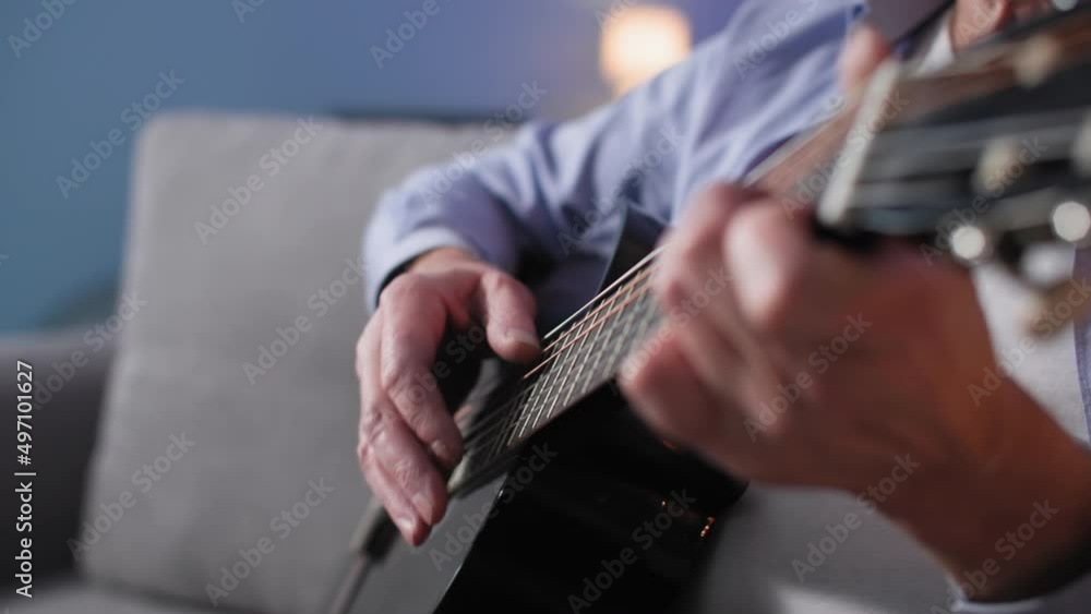 music hobby, elderly man playing acoustic guitar while sitting on sofa indoors, close-up music hobby, elderly man playing acoustic guitar while sitting on sofa indoors, close-up