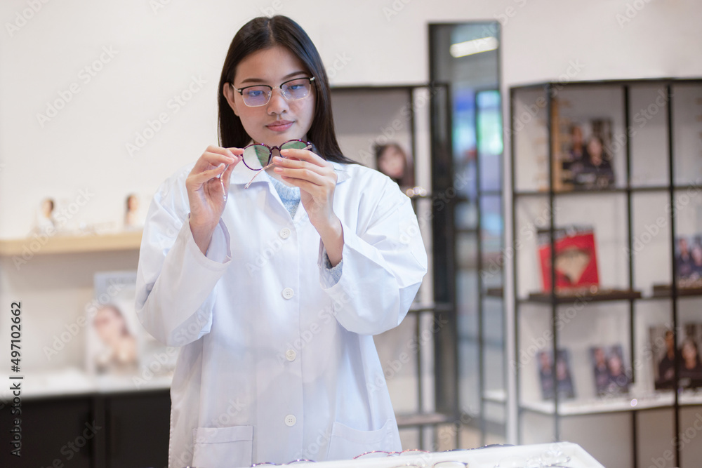 Female professional optician checking eyeglasses details in a shop Female professional optician checking eyeglasses details in a shop
