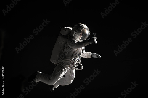 Fototapet Caucasian female astronaut using her mobile phone during spacewalk, messaging, t