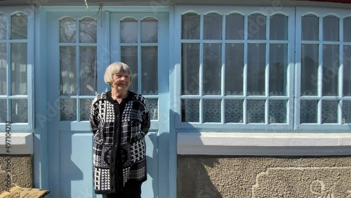 An old woman stands on the porch of a country house in Ternopil region, Ukraine