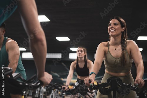 people on bikes in spinning class in modern gym, exercising on stationary bike. group of athletes training on exercise bike