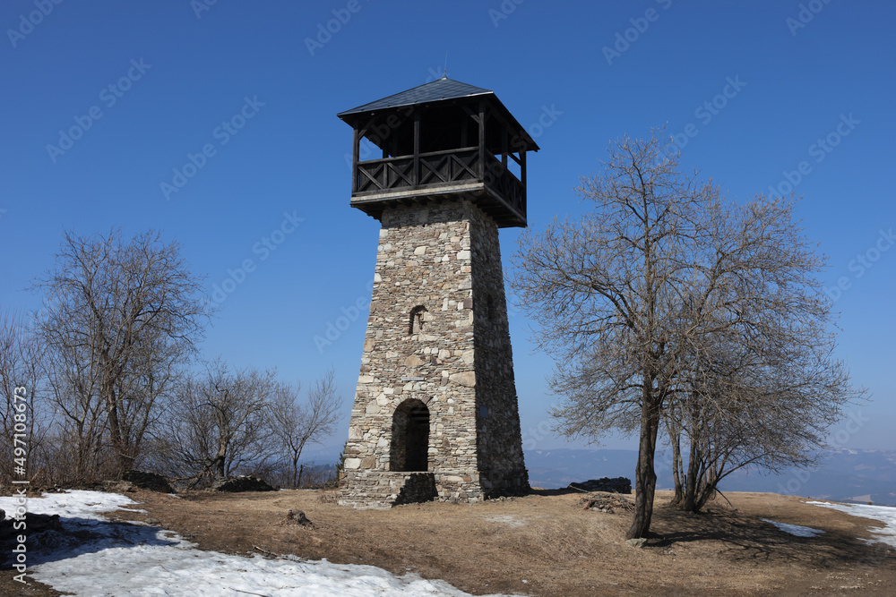 Lookout and observation tower on the top of hill, Martacky vrch, Zakopcie, Javorniky, Slovakia - tourist landmark and monument building made of stone. Bare tree and snow in the winter and early spring Lookout and observation tower on the top of hill, Martacky vrch, Zakopcie, Javorniky, Slovakia - tourist landmark and monument building made of stone. Bare tree and snow in the winter and early spring