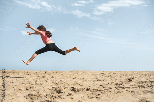 Happy girl jumping in the sand on the beach
