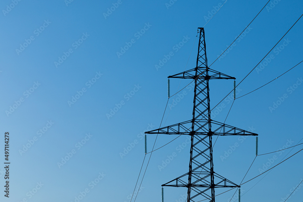 Background, view or scene of steel tower of electric main or electricity transmission line with the wires silhouette on background of clear blue sky