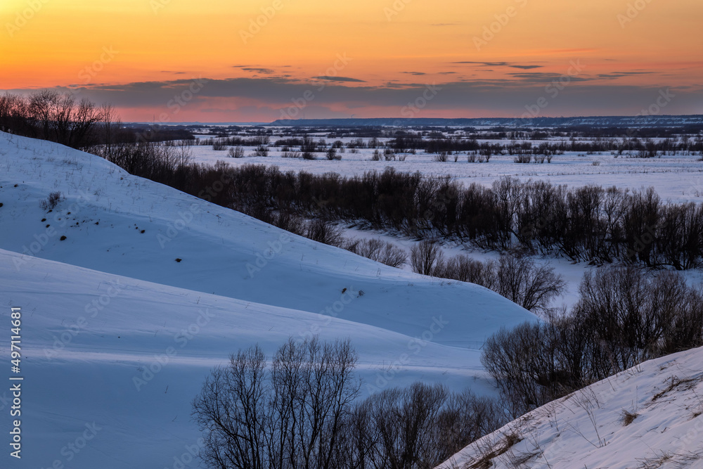 Sunset over snow-covered hills with trees on the slopes. dramatic sky Sunset over snow-covered hills with trees on the slopes. dramatic sky