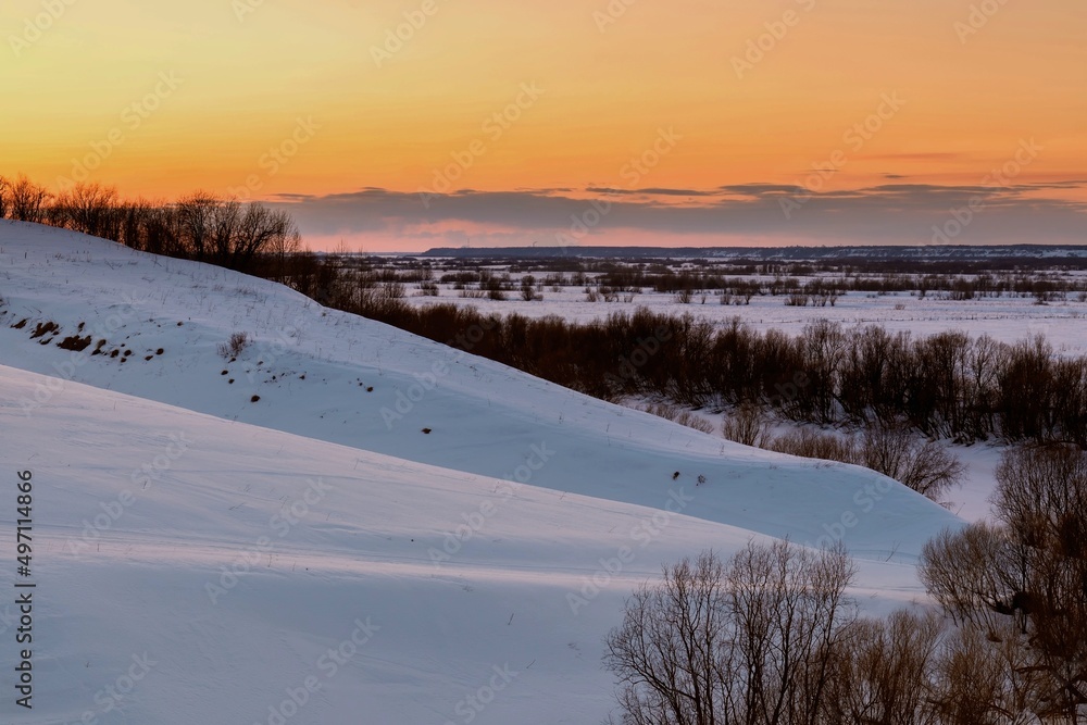Sunset over snow-covered hills with trees on the slopes. dramatic sky Sunset over snow-covered hills with trees on the slopes. dramatic sky