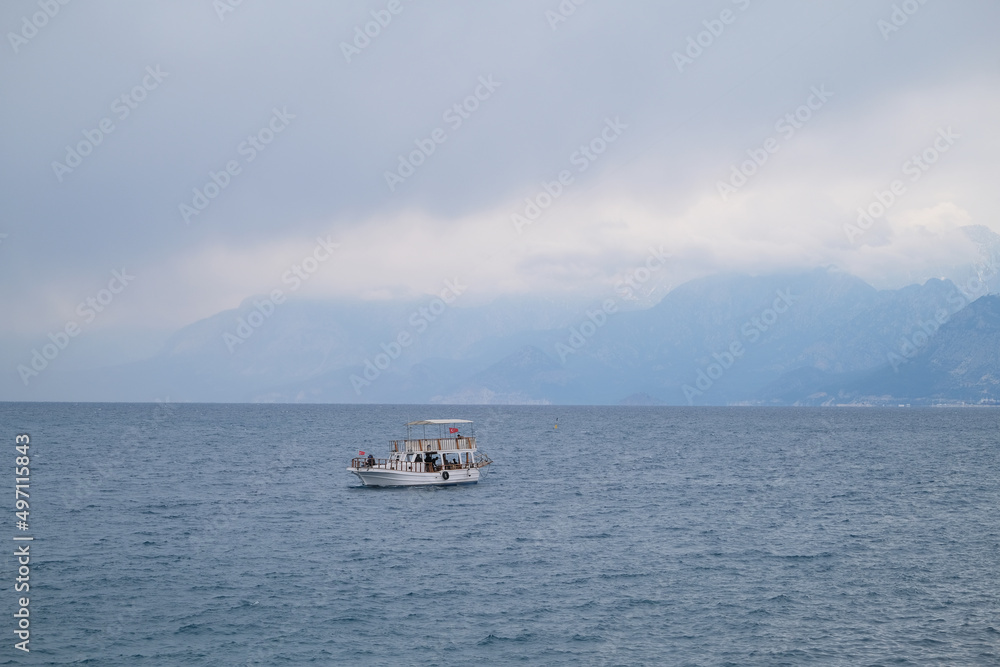 Boat with tourists in the sea against the backdrop of mountains in the fog