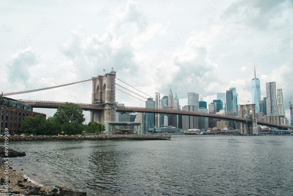 A stunning view of Manhattan skyline and Brooklyn bridge  across river Hudson with dramatic rain clouds in the sky