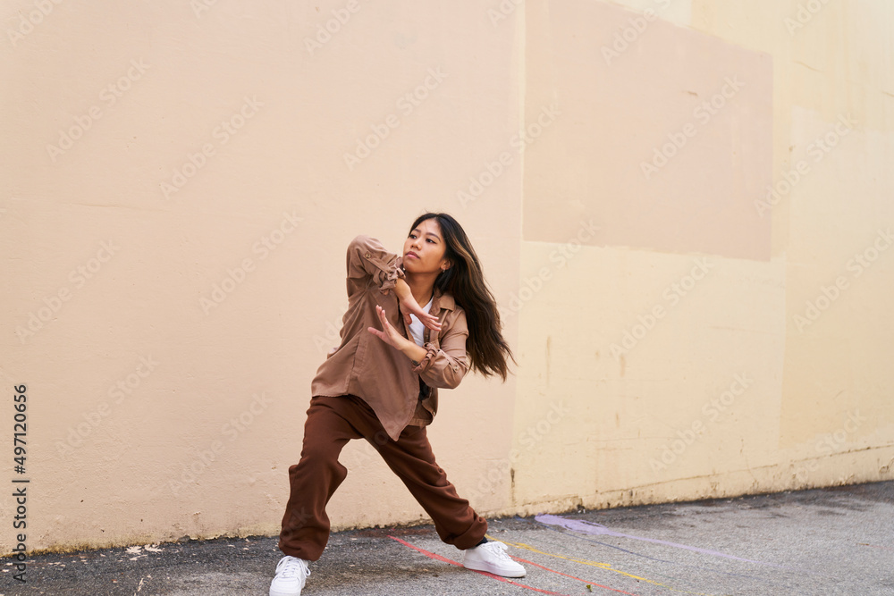 Woman dancing in front of beige wall side lunge