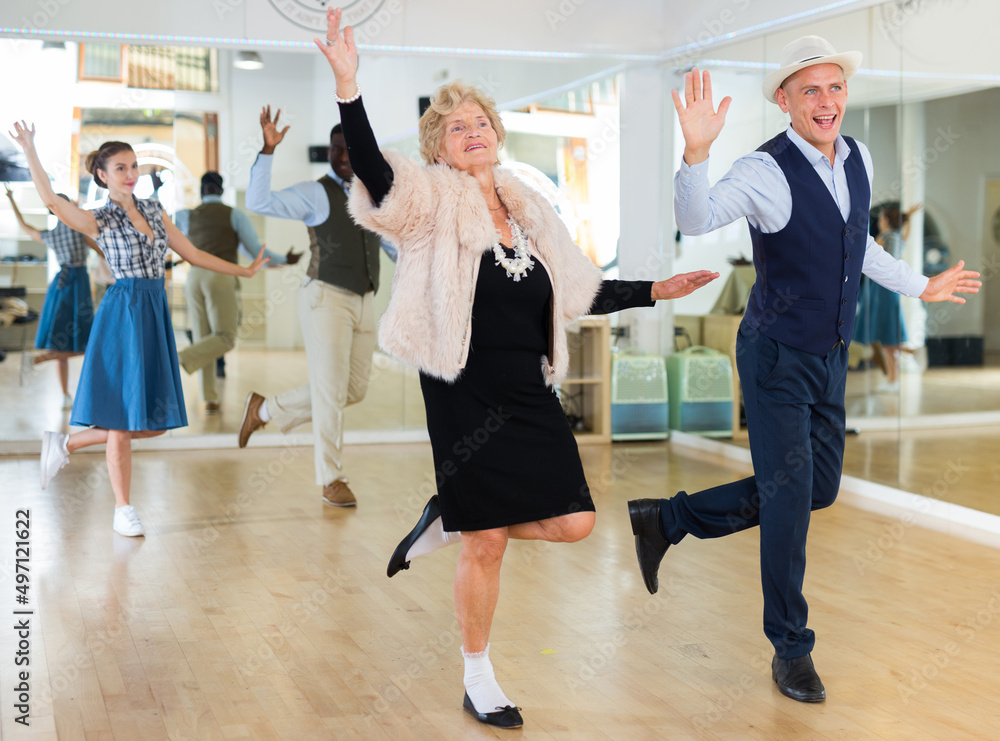Senior woman and younger man dancing swing in studio