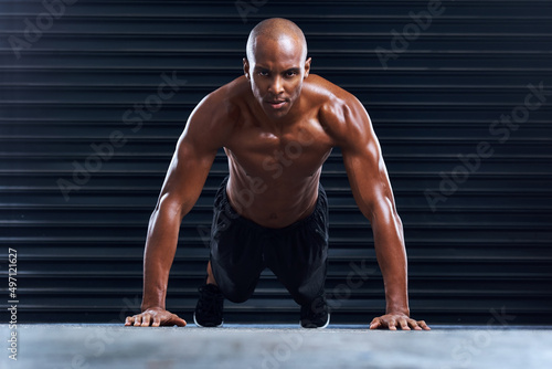 You get stronger with every workout. Shot of a sporty young man doing push ups.
