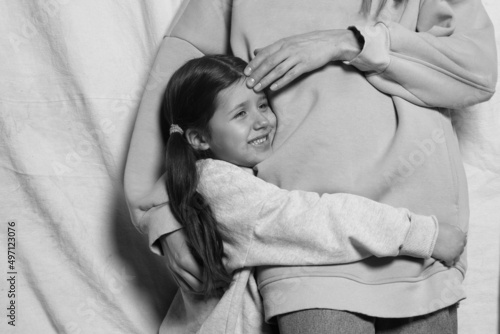 Mother woman in casual clothes hugging a cute baby girl. Mother, little daughter isolated on pastel wall background, studio portrait, mother's day, love, family, fatherhood, childhood, childhood 