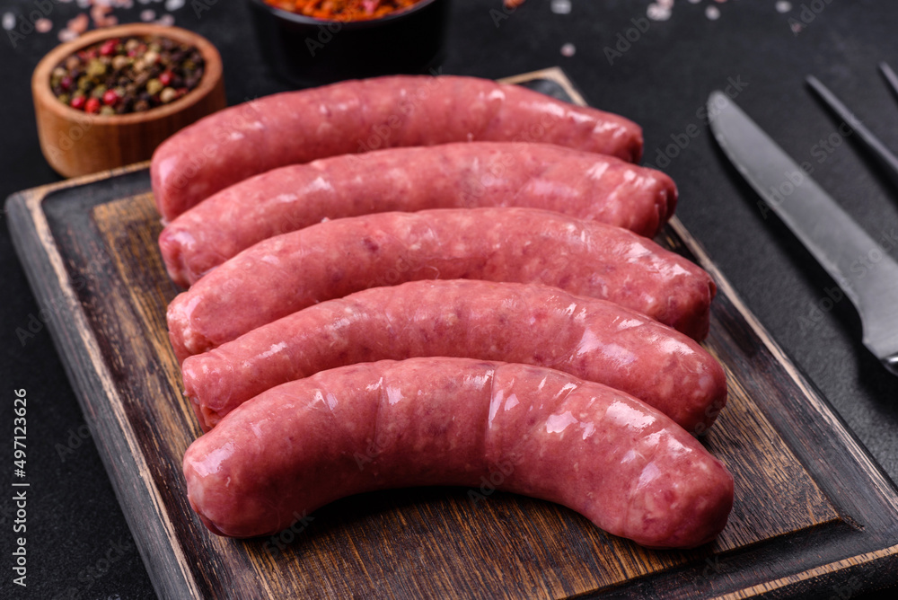 Raw sausages with ingredients on a cutting board on a stone background with copy space Raw sausages with ingredients on a cutting board on a stone background with copy space