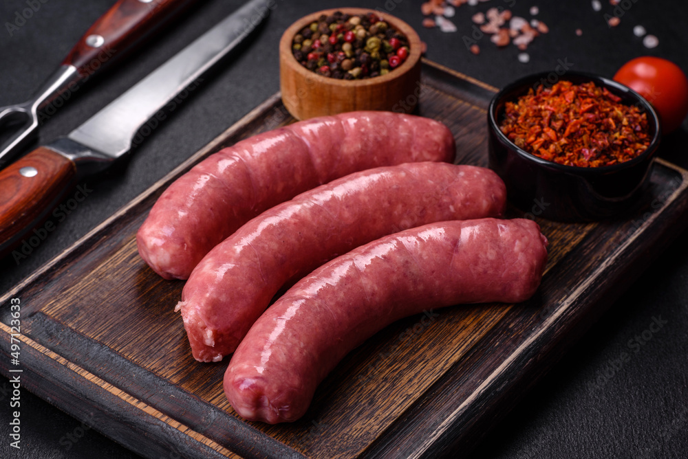 Raw sausages with ingredients on a cutting board on a stone background with copy space