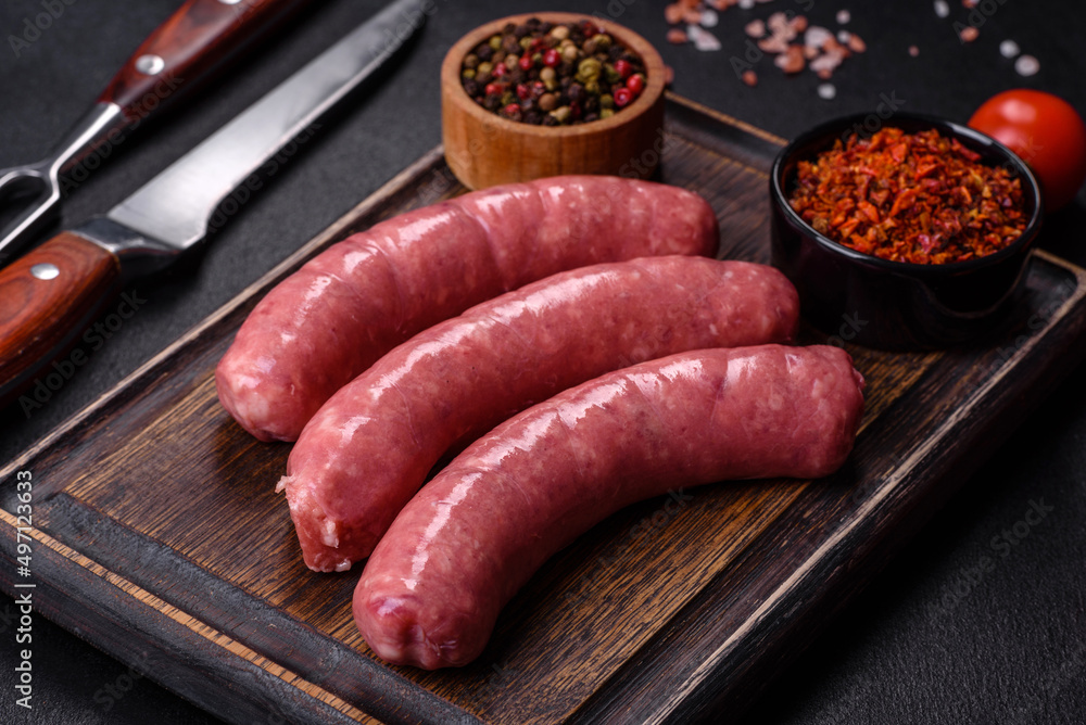 Raw sausages with ingredients on a cutting board on a stone background with copy space Raw sausages with ingredients on a cutting board on a stone background with copy space