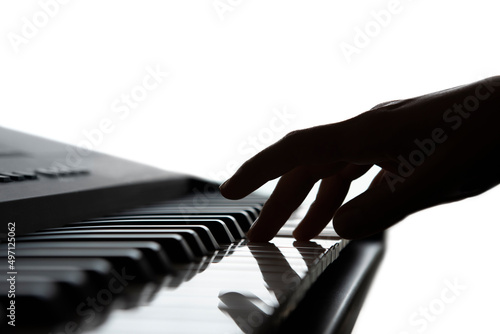 Silhouette of hand playing digital piano keys, concept of teaching to play a musical instrument online