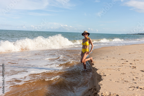 Fit women in a yellow bikini at the beach known as Pitinga, in Arraial d’ Ajuda, Bahia, Brazil  photo